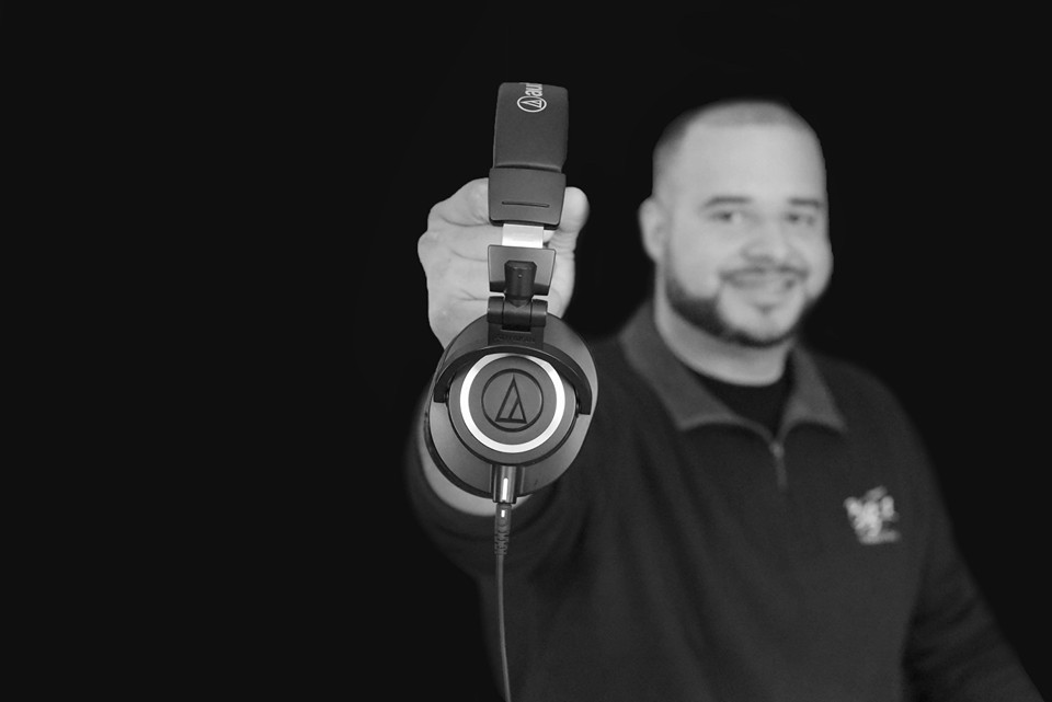 musical-strategic-partnerships-in-memphis-for-sound-production-dj-big3z-holding-quality-headphones-towards-camera-lens-for-updated-website-photography black and white smile first impression