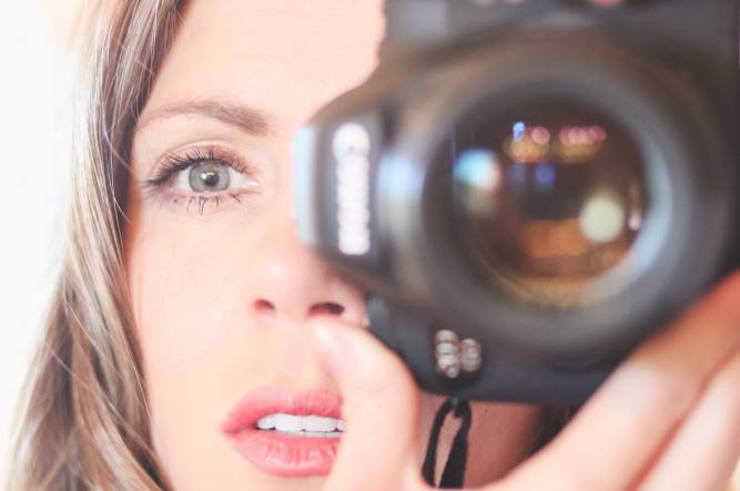 up-close image of danielle trask holding camera lens focusing with eyes fixated on client in phoenix az