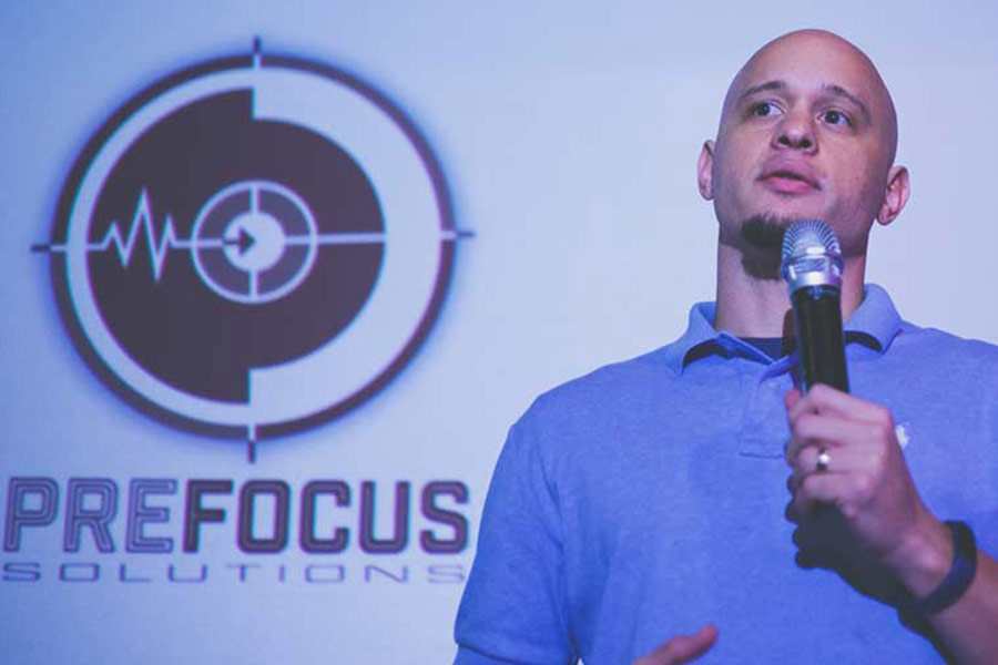  owner of prefocus solutions standing in front of audience of over 60 business owners at venue with stage in glendale arizona to help them develop a presence in the marketplace with simple tactics that drive recognition, trust and loyalty for any type of company across the united states of america