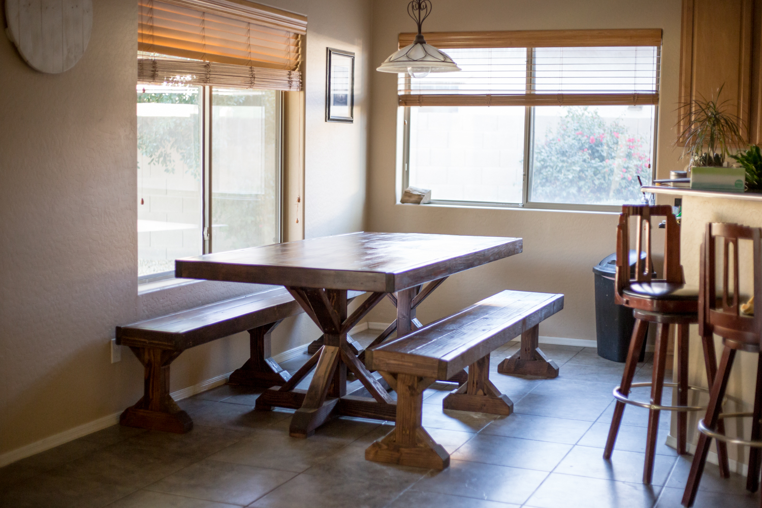 custom pine wooden kitchen dining table design in corner of home residence with matching benches and angled cuts with deep mahogany stain and clear coat finish by course grain in olive branch mississippi