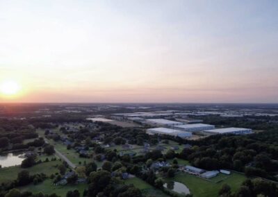 sun setting to the left as prefocus drone services in memphis capture olive branch skyline of trees and ponds commercial building pilot dusk