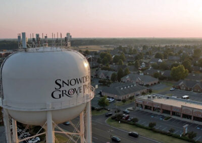 sun setting golden hour with water tower overlooking southaven city skyline residential neighborhoods from drone shadows