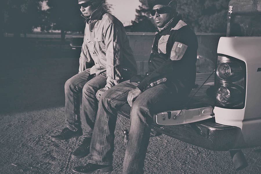 two worker buddies sitting on the tailgate of a truck after a long days work wearing name brand weather proof shirts beer in hand sun setting on beautiful midsouth day for creative direction with prefocus solutions on location