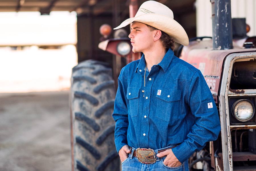 profile image for website branding imagery near memphis tennessee cowboy bull rider pro hands in pocket gazing to right in front of tractor at local cattle barn