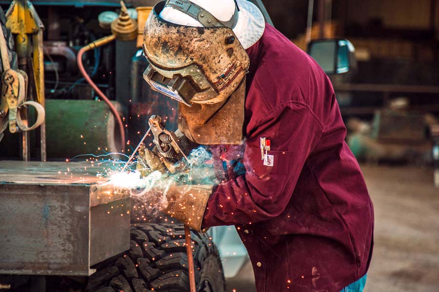 sparks and glowing flame of welding process in fireproof shirt by creative director near memphis tn looking to capture different blue collar workers for american made clothing line product strategy