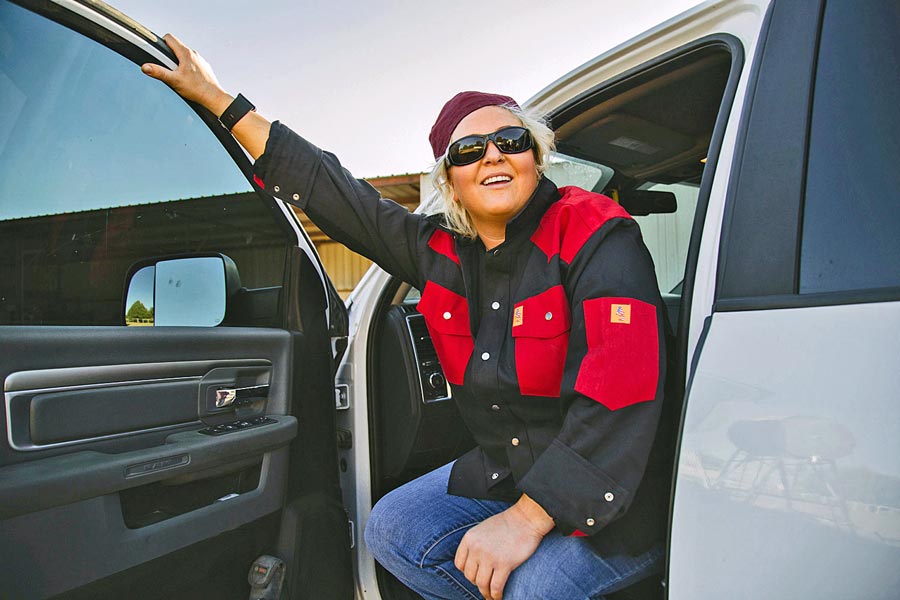 authentic image of blue collar woman hanging off side of truck at the end of the day in quality front pocket shirt for business prefocus creative direction near memphis tn